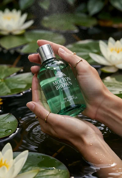 Close up of hands holding green bath gel bottle over dark lily