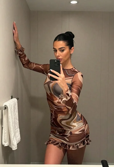 Woman taking mirror selfie in bathroom wearing marble patterned mini dress