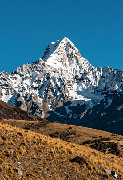 Majestic snow capped mountain peak dominating landscape against clear blue sky