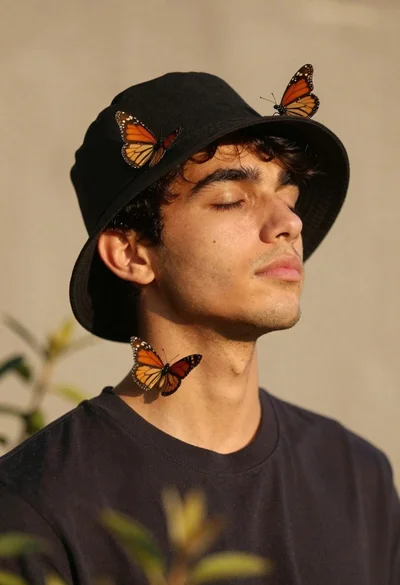 Serene portrait of young man with closed eyes and monarch butterflies