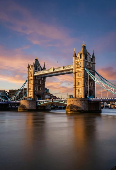 Wide view of tower bridge spanning river at sunset under dramatic colorful