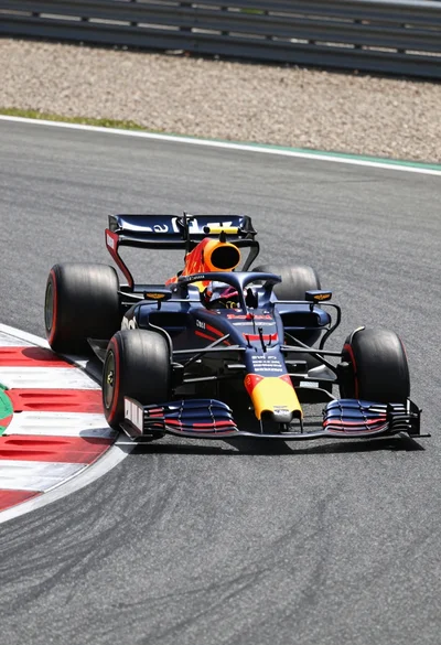 Dark blue red aston martin formula one race car cornering on asphalt