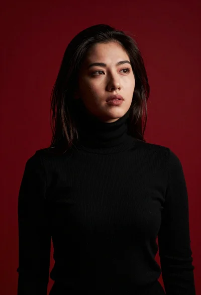 Moody portrait of woman in black turtleneck against red background