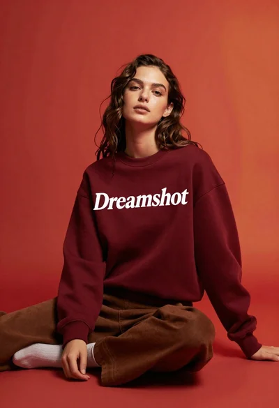 Studio portrait of woman in maroon sweatshirt against red backdrop