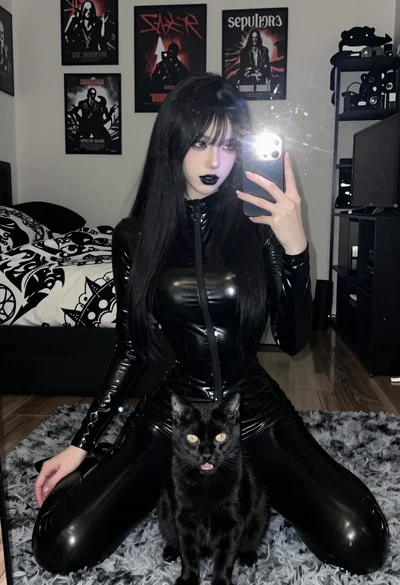 Young woman in black latex suit taking mirror selfie with cat present