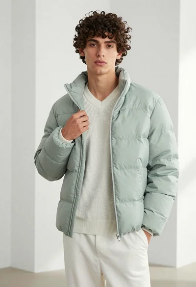 Young man in light green puffer jacket studio portrait