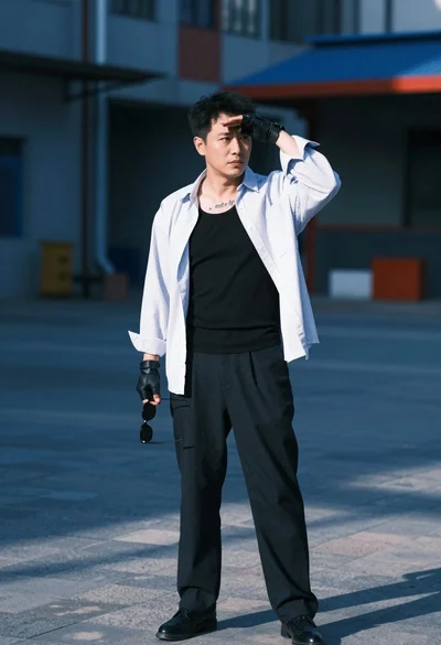 Man in white shirt standing outdoors shielding eyes with sunglasses