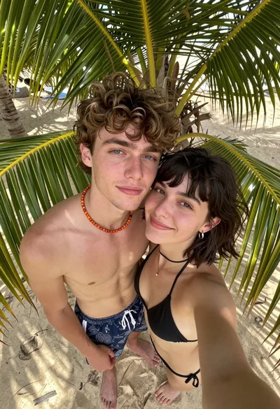 High angle selfie of young couple on sandy beach framed by palm