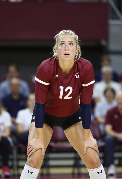 Blonde volleyball player in maroon uniform ready athletic stance indoors