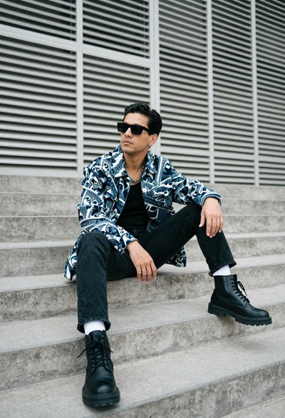 Man sitting on concrete steps against slatted wall low angle view