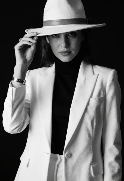 Confident woman in monochrome portrait wearing wide brimmed hat and white blazer