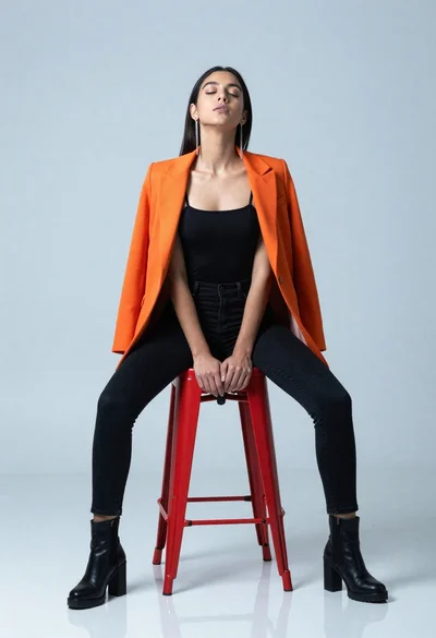 Woman in black outfit seated on red metal stool