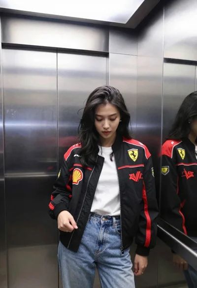 Young woman in black bomber jacket stands inside a stainless steel elevator