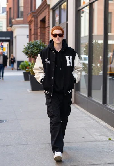 Stylish young person in varsity jacket on an urban brick sidewalk