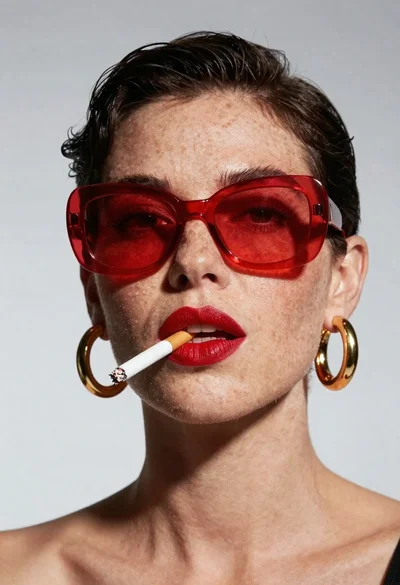 Studio portrait of woman with red sunglasses and freckles