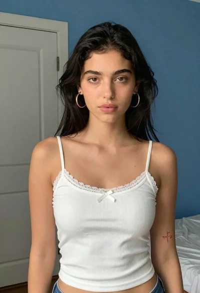 Young woman in white camisole top against blue wall indoors