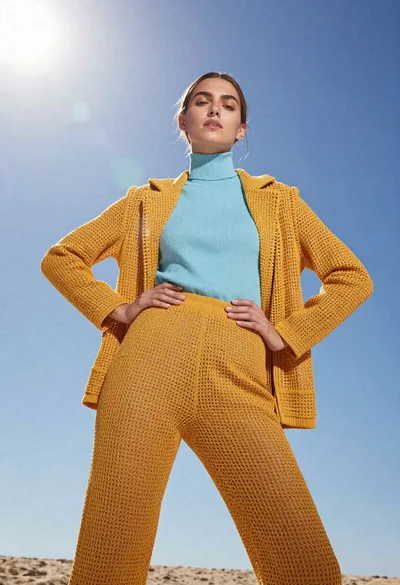 Model in yellow knit outfit against bright blue sky