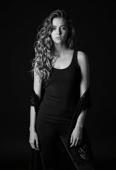 Monochrome portrait of young woman with wavy hair against black background