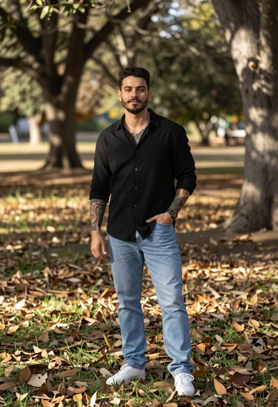 Man standing in wooded area with fallen leaves and filtered sunlight