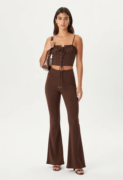 Young woman in chocolate brown two piece outfit posing in studio