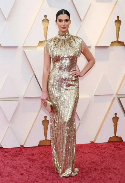 Woman in shimmering gold gown posing on a red carpet event
