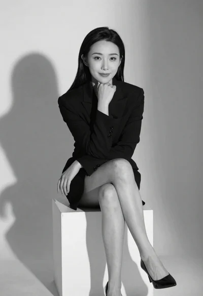 Black and white studio portrait of woman in blazer dress