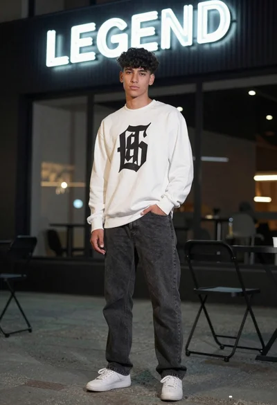 Young man in white sweatshirt standing near neon sign in urban setting