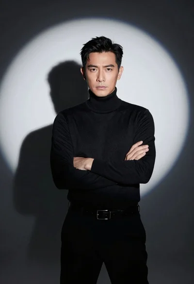 Handsome man in black turtleneck standing under dramatic spotlight against dark background