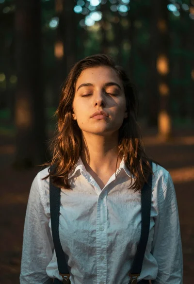Woman with closed eyes in sundappled forest