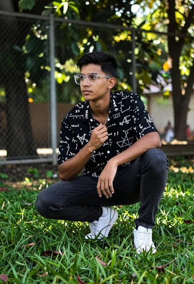 Young man crouching in lush grass near trees with mathematical shirt design