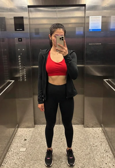 Fit woman taking a mirror selfie in an elevator interior