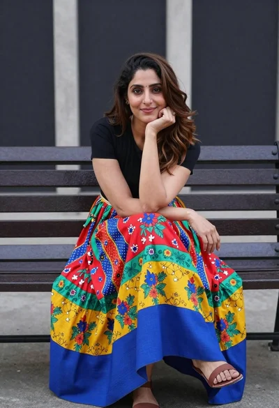Woman sitting on bench wearing colorful patchwork skirt in urban plaza