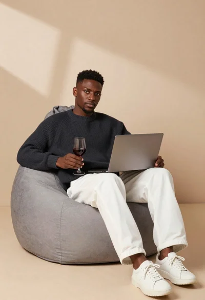 Black man sitting on beanbag chair with wine glass