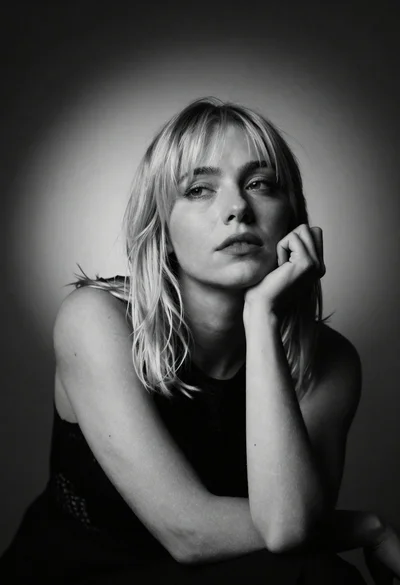 Black and white studio portrait of blonde woman resting chin thoughtfully