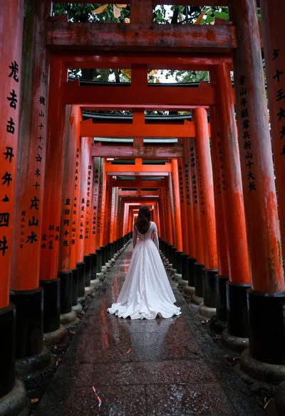 Woman in white dress at vermilion torii gate tunnel
