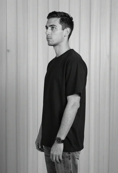 Black and white studio portrait of young man against wood wall