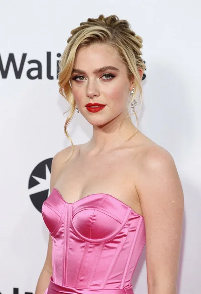 Glamorous portrait of blonde woman in pink satin dress against white wall