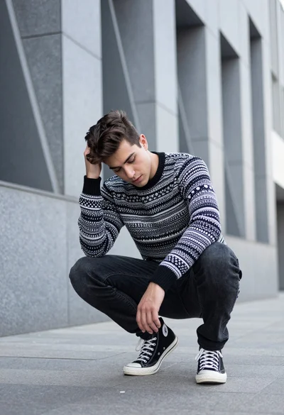 Young man crouching in modern urban setting against geometric stone architecture