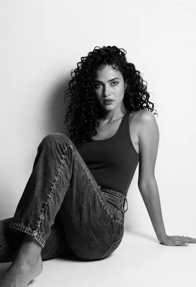 Black and white portrait of woman with curly hair against white wall
