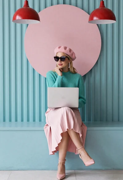 Blonde woman working on laptop in pastel teal room