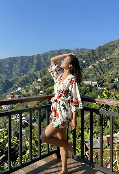 Woman in floral robe on wooden balcony overlooking green mountain valley