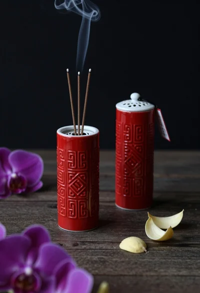 Still life composition of red incense holders with smoke on dark wood