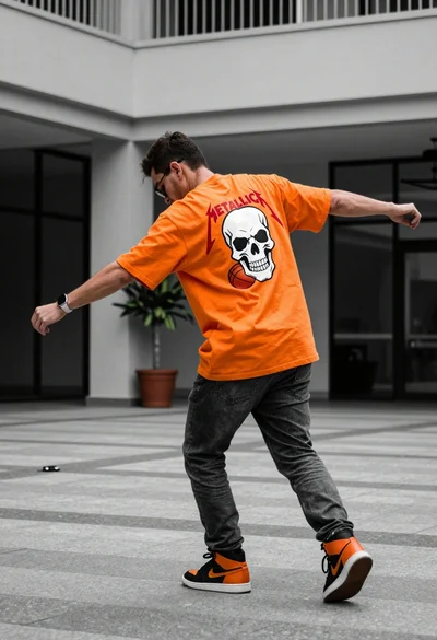 Man in orange tshirt leaning forward in urban plaza setting