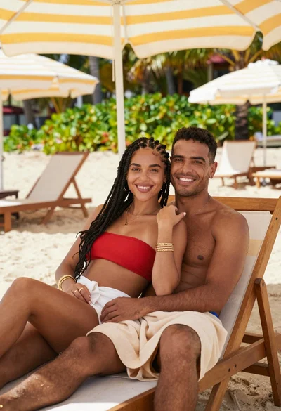 Smiling young couple relaxing together on lounge chair at sunny beach