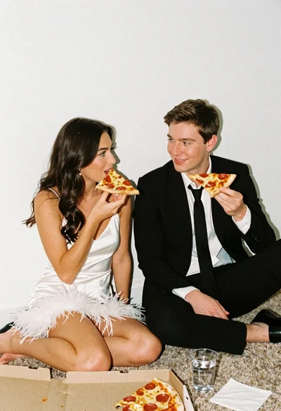 Young couple eating pepperoni pizza on a carpeted floor indoors