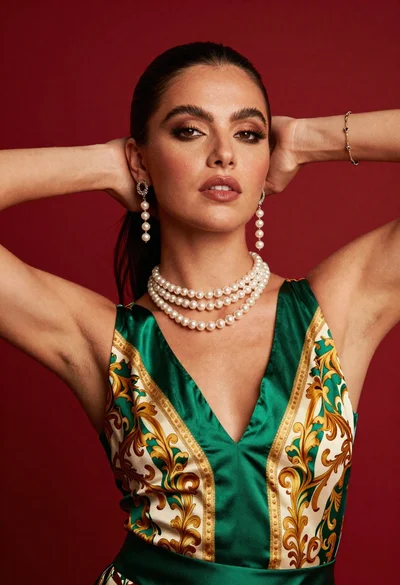 Glamorous woman posing in satin top against vibrant red studio backdrop