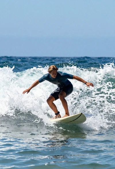 Young male surfer riding a powerful ocean wave on a light surfboard