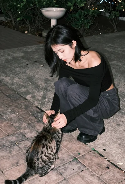 Young woman petting a cat outdoors on paved brick surface at dusk