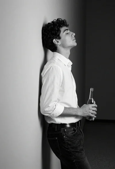 Young man in white shirt leaning against wall in quiet contemplation