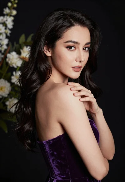 Glamorous portrait of woman with dark hair touching shoulder studio lighting